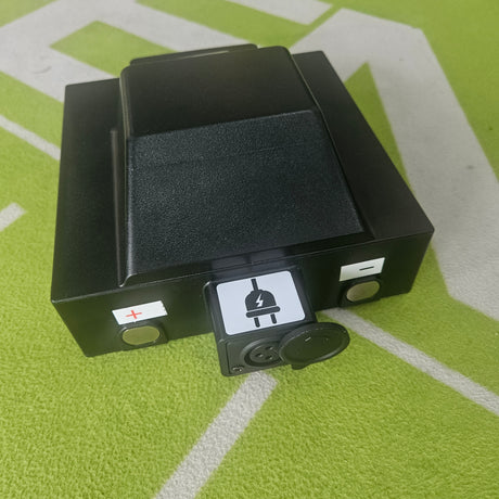 Black battery on a green surface