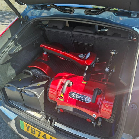 Red mobility scooter in the boot of a car with 'Sterling Sapphire' branding.