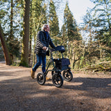 Man pushing a rollator through a forest path
